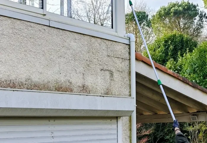 Technicien QUALIFICACE nettoyant les vitrages d’une véranda en hauteur