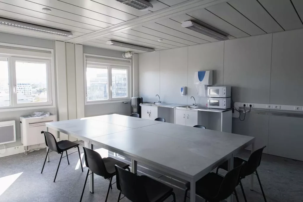 Réfectoire modulaire avec tables, chaises et kitchenette.